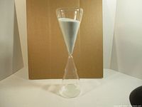 Front view of the large clear glass sand timer showing upper bulb filled with white sand.