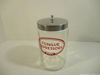 Full view of the clear glass jar with metal lid and 'TONGUE DEPRESSORS' label