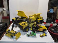 Overview of the entire lot of various Tonka construction trucks and smaller race cars and toy vehicles.