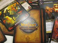 Close-up of several World of Warcraft Trading Card Game cards showing card faces with characters and abilities, with the card back also visible.