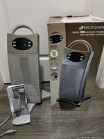 Front view of the Bionaire tower heater alongside remote, instruction leaflet, and original box showing the product image.