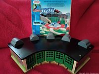 Grey semicircular roundhouse with green doors and black roof featuring 5 loading bays and a turntable mechanism on top, along with original box in background.