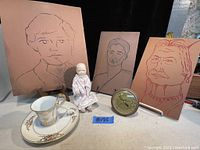 Three leather wall art portraits, tea cup and saucer, porcelain doll, and barometer arranged together