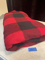 Photo of folded queen size red and black buffalo check blanket on a surface.