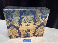 Closed gift box with blue and gold ornate damask design and Dolce & Gabbana label on front.