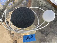Google Nest Mini smart speaker with fabric top, power cable, and round power adapter on glass table