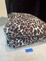 Folded leopard print blanket displayed on a surface, showing clear pattern and condition.