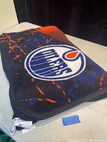Folded Edmonton Oilers fleece blanket showing logo and colors on a surface.