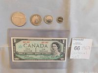 Four 1967 Canadian Centennial silver coins with distinct animal designs (goose, wolf, marten, songbird) and an archival plastic sleeve containing the 1867-1967 Canadian one dollar bill with serial number