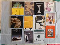 Overhead photo showing all 12 books and catalogues arranged in grid on fabric background.