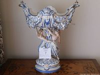 Front view of the tall ceramic fruit bowl with Neptune and Sea Goddess figures, showing intricate blue detailing and gold accents.