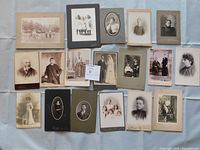 Full view of all 18 antique cabinet card photographs arranged on a surface.