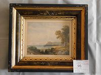 Front view of the watercolor painting in its frame showing the coastal landscape and castle ruins.