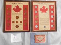 Two wooden framed Canadian coin displays side by side and a red paper bill in a clear holder below them.