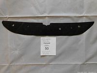 Full view of the black jade ceremonial harvest knife blade showing its shape and three holes for mounting.