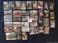Top side view showing 38 assorted antique post cards laid out flat displaying images of early 20th century portraits, landscapes, and vintage scenes.