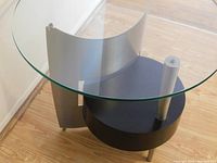 Three-quarter top view showing clear glass top and curved aluminum support