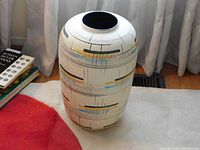 Full view of vase on carpet near curtain