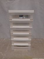 Front view of 6 drawer white plastic storage cart with labels on drawer fronts and organizer top section visible