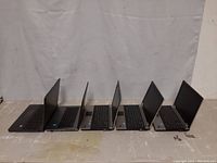 Side view of five HP laptops, two ProBooks and three EliteBook 8440p models, with open screens showing keyboards and displays.