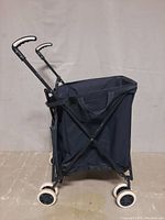 Side view of the foldable grocery cart showing the fabric bag, metal frame and white wheels