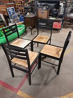 Four sturdy chairs shown grouped in an industrial setting, displaying black metal frames and wooden slatted seats.