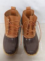 Front view of the boots showing tan leather upper and dark brown rubber lower with laces.