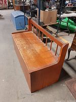 Wooden hall bench front view showing flat seat with surface scratches and vertical slatted backrest.