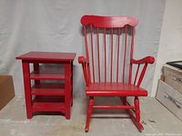 Red high back wooden rocking chair and side table together.