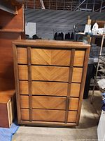 Front view of mid-century modern dresser showing five drawers with chevron-pattern veneer and vertical wood handles