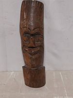 Frontal view of hand carved Polynesian mask showing carved facial features and base