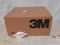 Closed cardboard box with 3M branding and a single sealed mask on top.