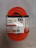 Front view of the 100 ft Woods extension cord showing length, branding and basic usage info on label.