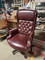 Front side view of burgundy leather executive chair showing button tufting and pillow top cushioning.