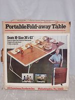 Photo of original packaging box showing product name, features, and marketing image of the fold away table set for 10 persons.