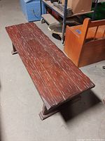 Top and side view of rustic wooden bench showing the textured wooden surface with multiple scratches and distressed marks on the seating area.