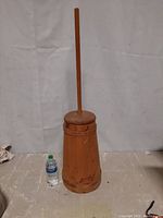 Full view of the wooden butter churn alongside a water bottle for scale, showing the general shape and condition.