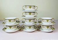 Eight pairs of Noritake bouillon cups and saucers stacked and arranged in three stacks showing the full set.