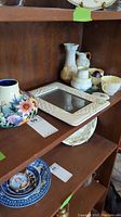 Shelf displaying Belleek porcelain pieces with a small picture frame and the floral Adeline vase.