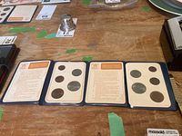 Two open vinyl holders each displaying a complete set of Britain's first decimal coins along with informative cards