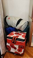 Photo showing cooler bag with red poppy flower print and two rolled sleeping bags behind it