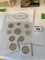 Overview of 1971 Canadian coin set displaying various coins including commemorative dollars, housed on a white surface with the Royal Canadian Mint envelope seen above the coins.