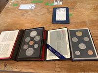 Two boxed Royal Canadian Mint coin sets side by side on wood surface, showing sets in their cases with all coins visible.