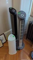 Three items in lot: two tower fans and one humidifier near corner of room.