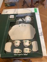 Original boxed Belleek miniature Shamrock tea set showing front packaging and arrangement of items inside including teapot and trays.