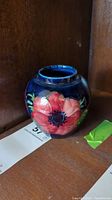 Front view of the small Moorcroft vase showing bright red and pink floral design against dark blue background.