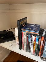 Photo of Blu-ray and DVD movie cases stacked upright showing various titles including Shrek, Spider-Man 3, Miss Congeniality, The Godfather Trilogy, and others.