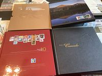 Four stamp albums/folios for Canadian stamps including the red Collection Canada 10, grey Collection Canada, brown folder with embossed Olympics logo and a blue stamp album.