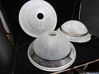 Photo showing three marbled glass lampshades in various sizes and styles on a black surface