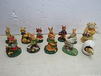 View of 12 miniature collectible figurines including rabbits, chicken, egg, and angel on plain background showing details and base decorations.